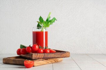 Glass of bloody mary with celery and tomatoes on white tile table