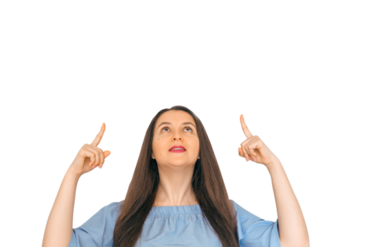 A young, attractive girl looking up and pointing with index finger at copy space. A sign, an empty space for advertising, inscription, design. White background.