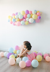 A little happy  girl with colorful balloons on a white background, studio shoot. Celebrations, birthday and playing concept. Top view