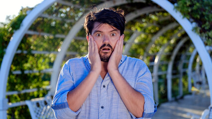 A middle-aged, dark-haired businessman wearing a shirt is looking at the camera in a sunny,...