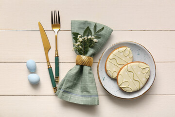Beautiful table setting with sweet cookies, Easter eggs and gypsophila flowers on white wooden...