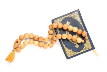 Koran with prayer beads on white background. Ramadan celebration