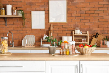 Jars with different spices, plant and food on table in kitchen