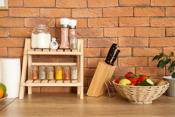 Stand with different spices, knives and vegetables on counter in kitchen