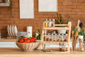 Stand with different spices and vegetables on table in kitchen