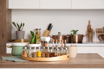 Jars with different spices and plants on table in kitchen