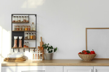 Shelves with spices on light wall in kitchen interior