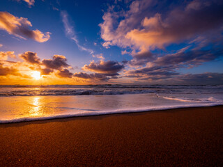 Dramatic sky with high contrast pink clouds with sunlight reflections compliment the shoreline of...