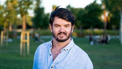 A middle-aged, dark-haired businessman wearing a shirt is smiling at the camera in a sunny,...