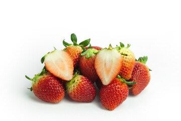 strawberries are arranged in a heart shape on a white background. The berries are red with green stems, some showing a transition to lighter, unripe areas. The image is a top-down view