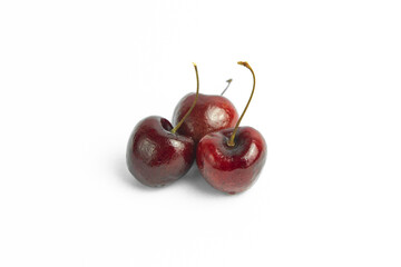 This image shows three dark red cherries against a plain, light background
