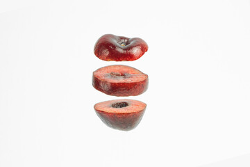 This image shows a single red plum cut into three horizontal slices, arranged vertically in the center of a white background