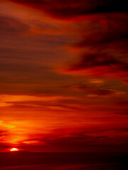 Dramatic sky filled with orange, red and various hues reflects against the Pacific Ocean horizon