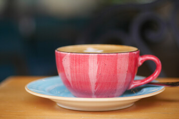 Brightly colored coffee cup on a saucer at a cafe table
