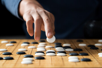 close up of player hand make a move in Go game(Weiqi),Traditional trategy board game