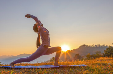 Young beauty girl doing yoga pose on mountain sunset background