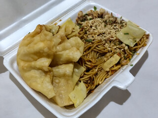 Mie Gacoan, Fried Noodles with a Typical Indonesian Spicy Level, served with Fried Dumplings, sprinkled with chicken and other toppings.