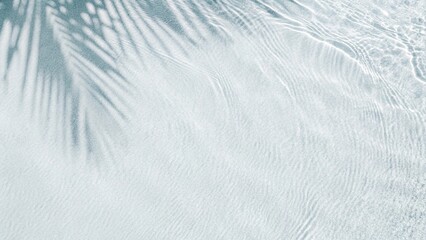 Obraz premium Palm leaf shadow on abstract white sand beach background. Sunlight on water surface, a beautiful abstract background concept banner for summer vacation at the beach. Top view of tropical leaf shadow