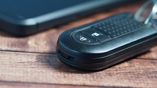 Car key fob on wooden surface with smartphone nearby