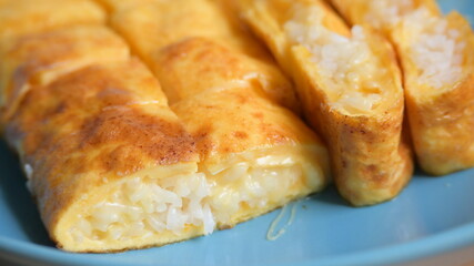 roll omelette stuffed with chesse and rice on blue plate, delicious food in the morning