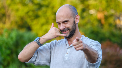 A middle-aged handsome businessman in a tree-lined park on a summer day, looking at the camera with...