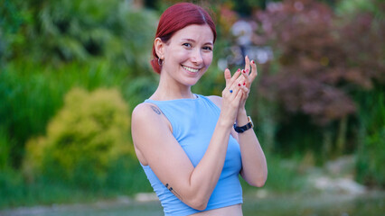 A young, beautiful, brown-haired businesswoman in a tree-filled park on a sunny summer day, looking...