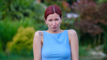 A young and beautiful businesswoman on a summer day in a wooded park, looking at the camera while...