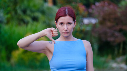 A young, beautiful businesswoman  in a leafy park on a sunny summer day, looking at the camera and...