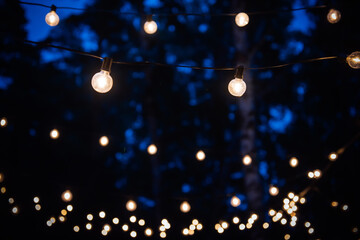 Sphere Light bulb, represent unity and harmony, on electricity wire, decorated by lovely family for holiday or anniversary celebration, illuminate in the outdoor dinner festival party at night