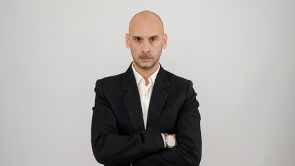 In a studio setting, a middle-aged businessman wearing a suit is standing in front of a white background, crossing his arms over his chest and looking at the camera with an angry expression