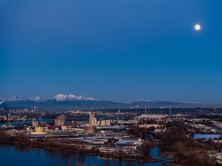 Obraz premium Delta BC Canada - February 11th 2025: Sunset at Deas Island Regional Park waterfront with mountain and moonrise
