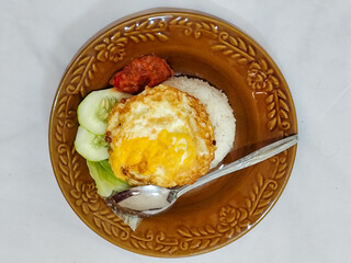Lalapan Telur.  Rice with fresh vegetables, with traditional Indonesian chili sauce, with fried egg side dish, white background.