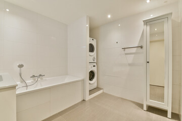A sleek and contemporary bathroom featuring a bathtub, laundry appliances, and minimalist design elements that maximize space and functionality.