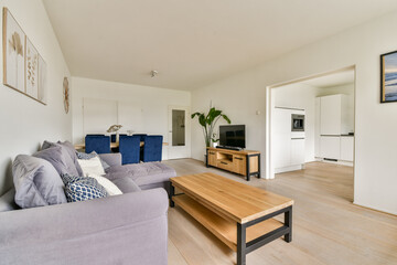 A minimalist living room showcasing comfortable gray furniture, a wooden coffee table, and a bright open space that blends modern design with simplicity.