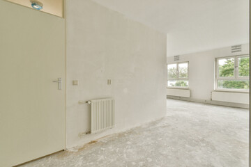 A bright, minimalist interior featuring large windows and a neutral color palette. The simplicity of the design emphasizes natural light and open space.