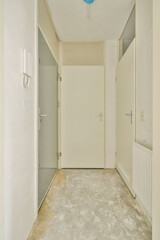 A spacious, minimalistic hallway featuring white walls and multiple doors. The floor is bare, suggesting an unfinished look, inviting creativity and potential.