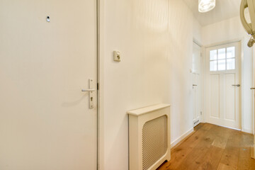 Bright and airy hallway featuring white walls and wooden flooring. The space is accented by modern light fixtures, creating a welcoming atmosphere.