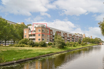 Fototapeta premium Contemporary residential architecture bordered by greenery and a tranquil water channel creates a serene urban environment.