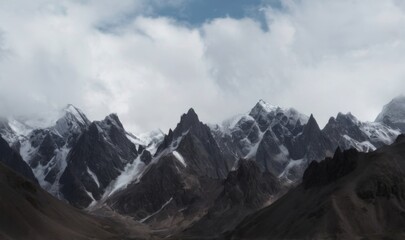 Obraz premium Snowcovered mountain range under fluffy clouds showing dramatic, aweinspiring landscape with jagged peaks and deep valleys.