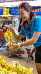 A young red-haired woman happily shopping at a fruit and vegetable bazaar on a summer day