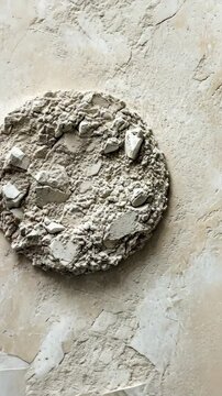 Textured round surface composed of gray material with small fragments on a light background