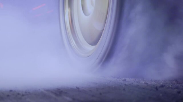 Smoke on wheel of drag racing car at starting line.