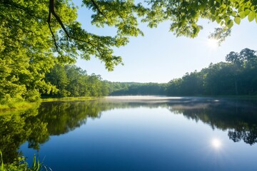 Obraz premium Tranquil lake at sunrise with mist and lush foliage.