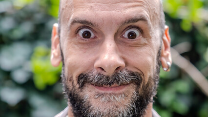 An extreme close-up headshot of a middle-aged man making funny facial expressions while looking at the camera