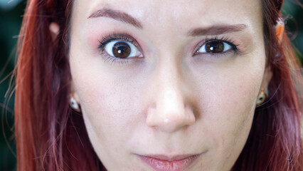 A very close-up headshot of a young woman making funny facial expressions while looking at the camera