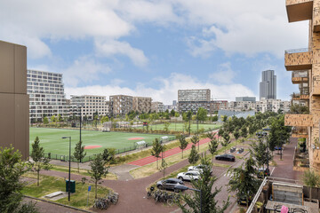 A vibrant urban scene showcasing modern architecture alongside expansive green fields and pathways,...