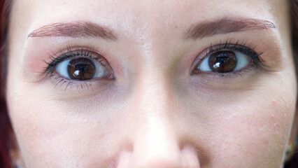 A very close-up headshot of a young woman making funny facial expressions while looking at the camera