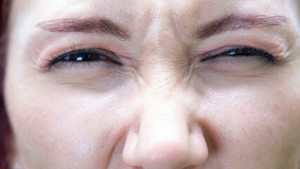 A very close-up headshot of a young woman making funny facial expressions while looking at the camera