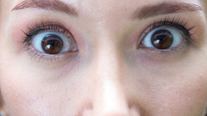 A very close-up headshot of a young woman making funny facial expressions while looking at the camera