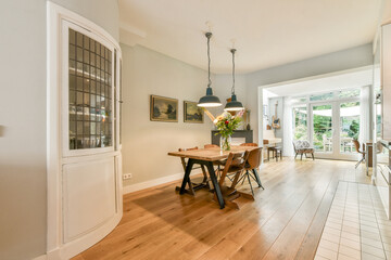 Stylish dining area featuring a wooden table, contemporary chairs, and large windows for ample natural light, creating a warm atmosphere.